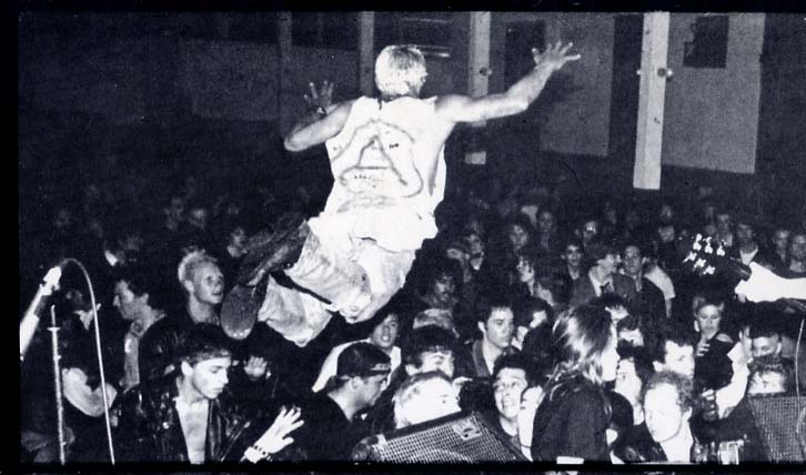 This is a photo of a dude doing a nice stagedive at a norther Cal. PunK gig early 80's